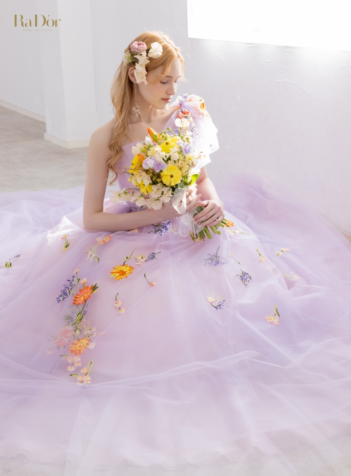 色鮮やかな小花刺繍をあしらったラベンダーカラーのチュールドレスを着てブーケを持つ花嫁
