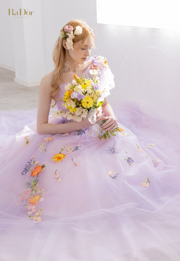 色鮮やかな小花刺繍をあしらったラベンダーカラーのチュールドレスを着てブーケを持つ花嫁