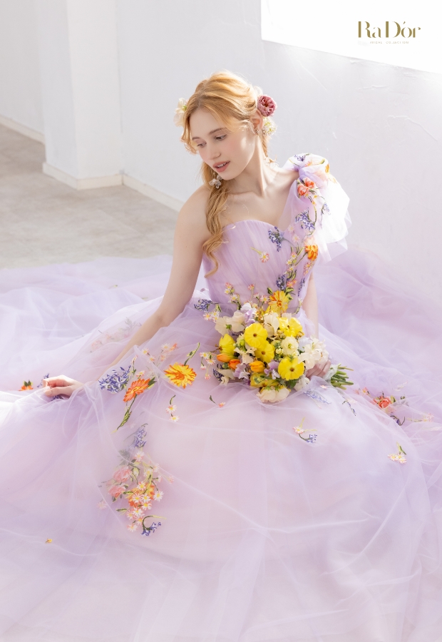 色鮮やかな小花刺繍をあしらったラベンダーカラーのチュールドレスを着てブーケを持つ花嫁