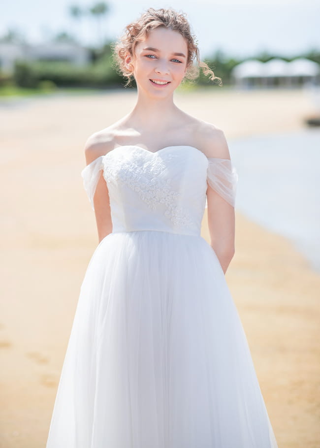 ビーチに映えるプリンセスラインのドレスを着て微笑む花嫁