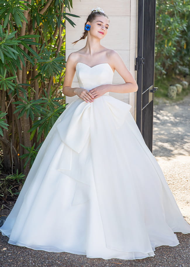 大きなリボンモチーフが可愛らしさを演出する白のプリンセスラインのドレスを着た花嫁