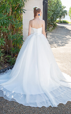 大きなリボンモチーフが特徴的な白のプリンセスラインのドレスを着た花嫁の後ろ姿