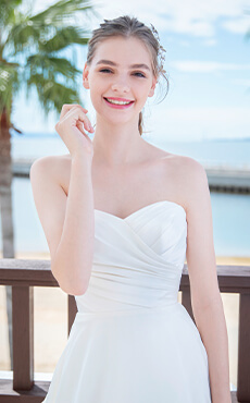 シンプルなデザインのスレンダーラインのドレスを着て微笑む花嫁のアップイメージ