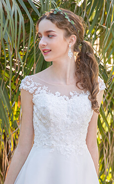 花柄のレースがあしらわれたスレンダーラインのドレスを着た花嫁のアップイメージ