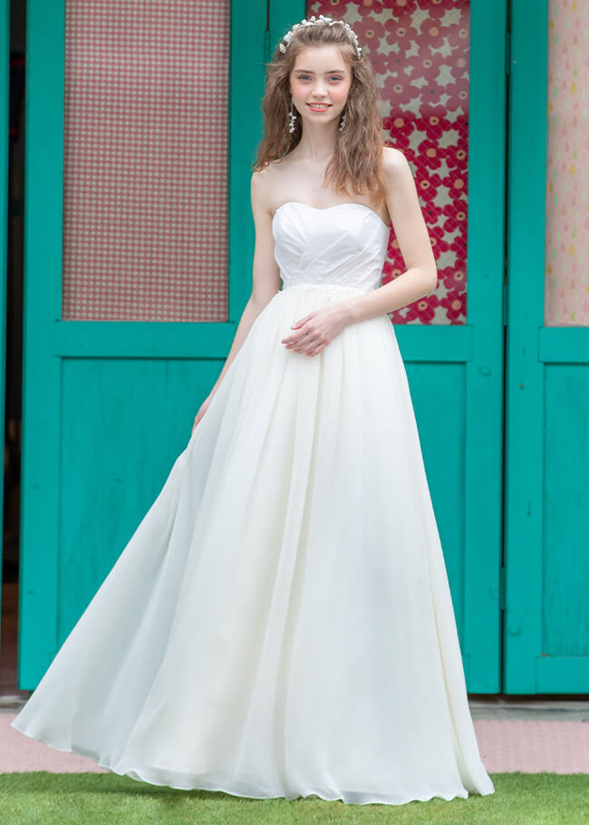 軽やかでスリムなアイボリーのスカートが印象的なAラインウェディングドレスを着た花嫁